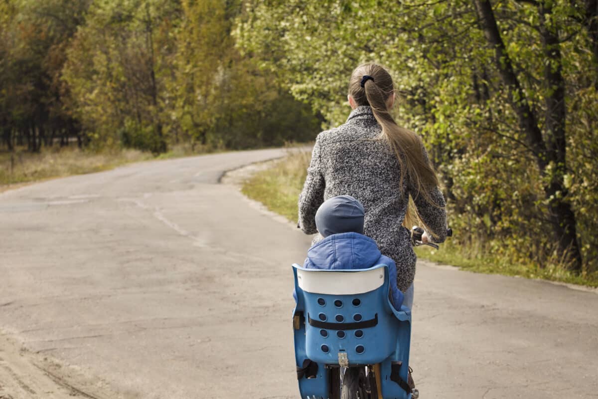 Une mère et son enfant profitent d'une balade en vélo, en toute sécurité grâce à leur porte-bébé adapté."