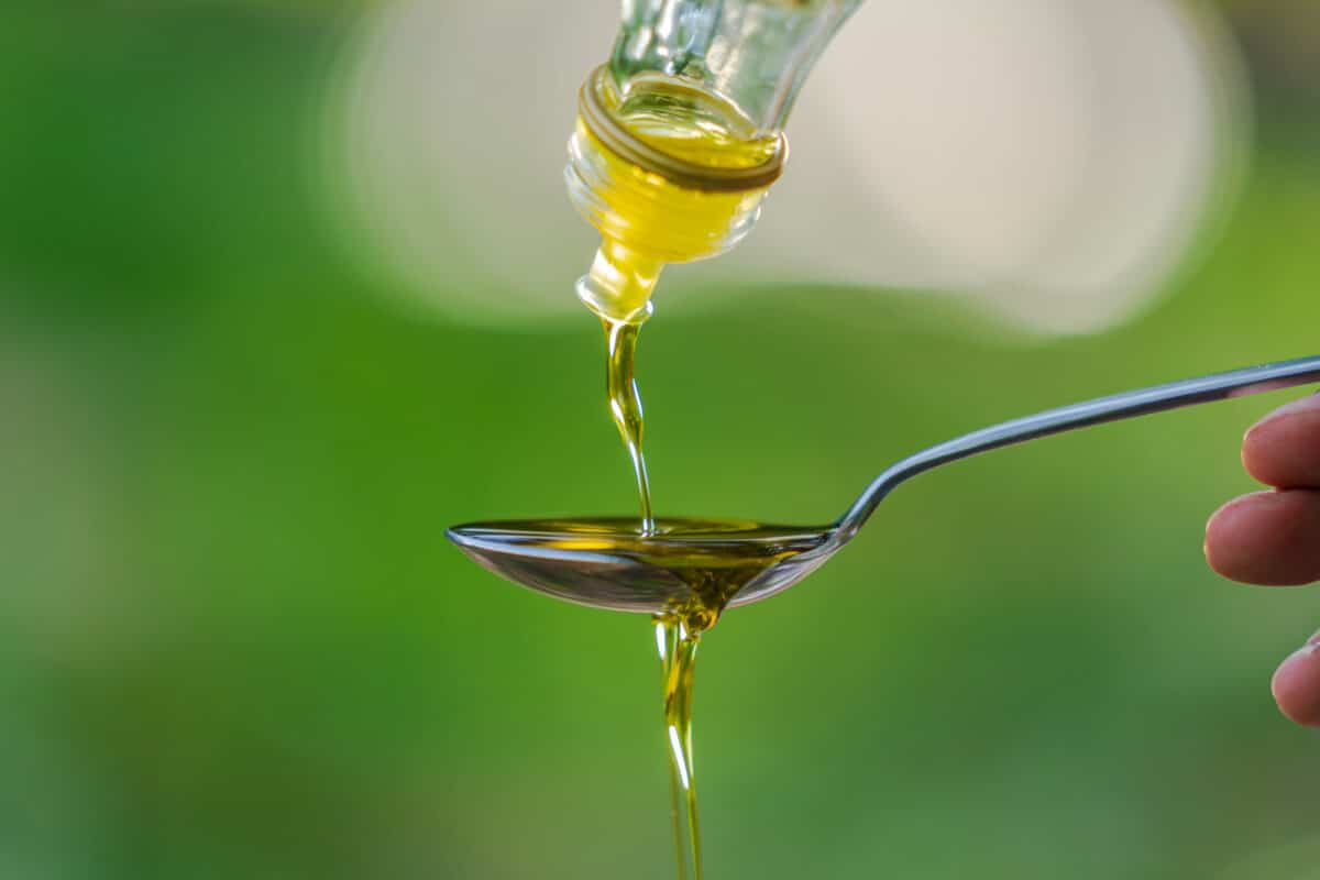 Un moment suspendu : l'huile délicatement versée sur une cuillère évoque une saveur authentique