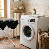 Quatre culottes menstruelles noires sèchent sur un étendoir près d'un lave-linge, dans une salle de bains